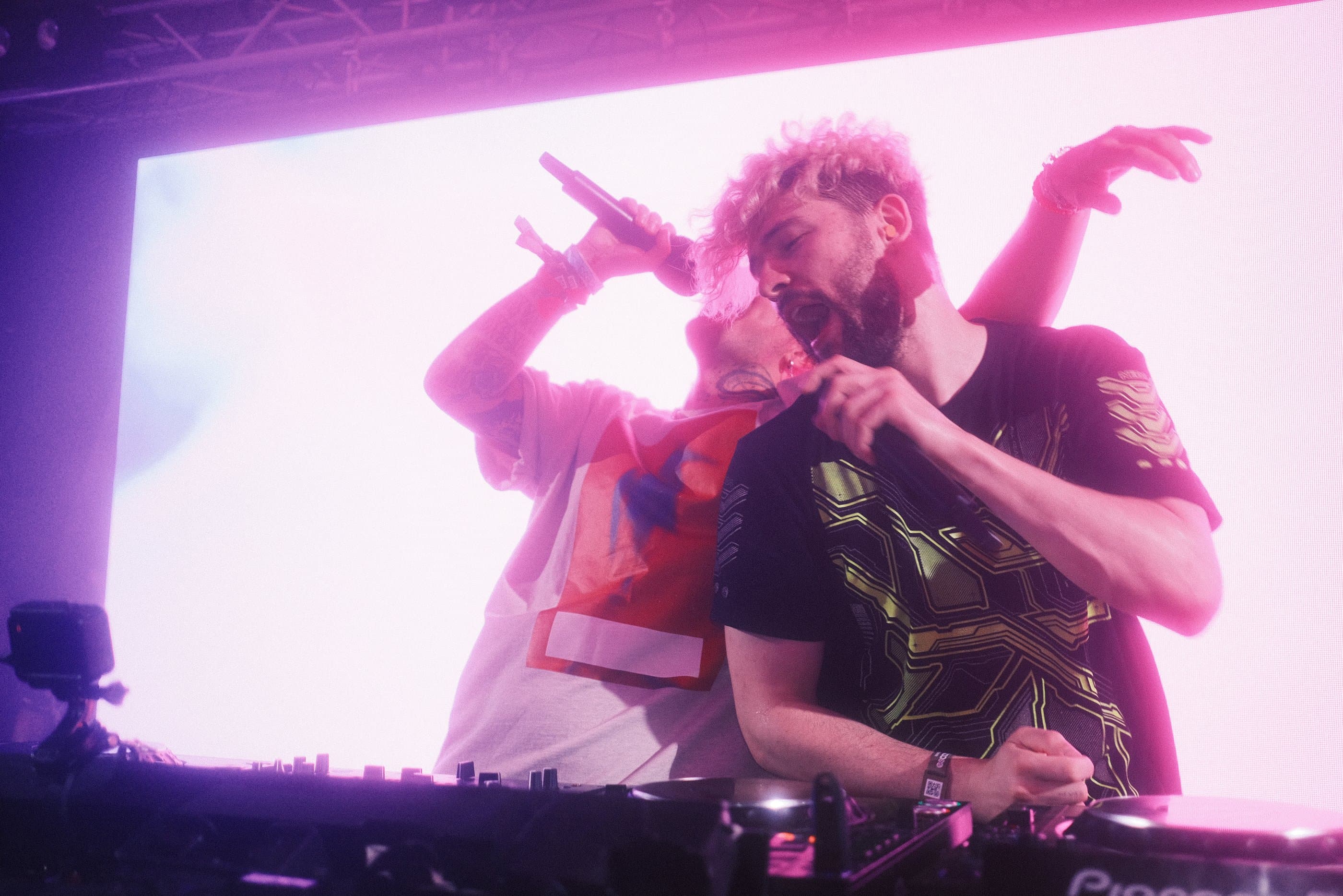 Two artists performing together under pink stage light